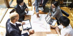 Group of executives around a table examining a plan for a new learning technology project